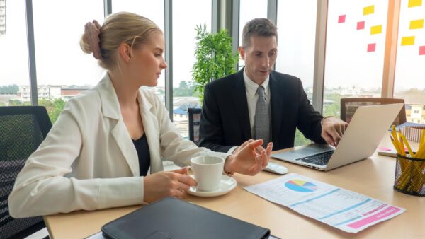 young business team working together at office. Manager pointing at a chart and explaining the analysis about business strategies. Top view shot of business hand shake